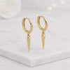 Golds pike hoop earrings in14K solid gold with polished huggie hoops and pointed drop designs how nona cleanmarble surface ideal for minimalist jewelry loverss